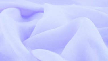 Dönen bir vitrin üzerinde ince mısır çiçeği mavi şifon kumaşının yumuşak kıvrımlarının yakın çekim görüntüsü. Moda, tasarım, kumaş teması üzerine aksesuar dikebilen tekstil arka planı.
