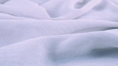 Dönen bir vitrin üzerindeki ince mavi şifon kumaşın yumuşak kıvrımlarının yakın görüntüsü. Moda temalı dikiş aksesuarları ile tekstil arka planı.