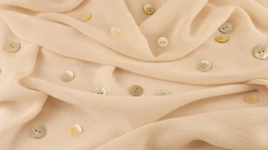 İnce kabuklu beyaz şifon kumaş rengi şifon ve vitrindeki doğal inci düğmelerin üst görüntüsü. Moda temalı dikiş aksesuarları ile tekstil arka planı.