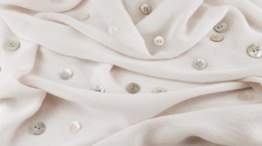 İnce beyaz duman rengi şifon kumaş kumaş ve vitrindeki doğal inci düğmelerin yakın çekim görüntüsü. Moda temalı dikiş aksesuarları ile tekstil arka planı.