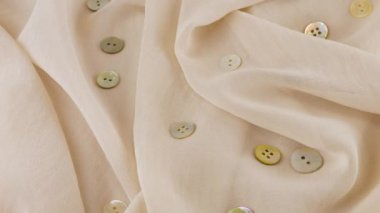 İnce pembe tuz beyaz şifon kumaş rengi şifon ve vitrindeki doğal inci düğmelerin üst görüntüsü. Moda temalı dikiş aksesuarları ile tekstil arka planı.