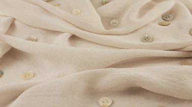 İnce pembe tuzun beyaz şifon kumaş renginde yakın plan görüntüsü ve vitrindeki doğal inci düğmeler. Moda temalı dikiş aksesuarları ile tekstil arka planı.