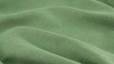 Viridian yeşil keten kumaşının yumuşak kıvrımlarının yakın görüntüsü. Tekstil arka planı vitrinde döner. Moda, tasarım, doğal kumaşlar, renk tonları teması üzerine arka plan.