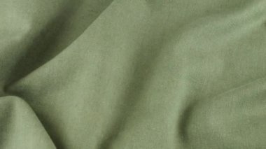 Viridian yeşil keten kumaşının yumuşak kıvrımlarının üst görüntüsü. Tekstil arka planı vitrinde döner. Moda, tasarım, doğal kumaşlar, renk tonları teması üzerine arka plan.