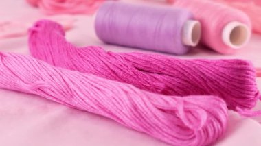Pamuk kumaşın yakın görüntüsü, düğmeler ve iplik makaraları, diş ipi, pembe rengin farklı tonlarında iplik. Tekstil arka planı vitrinde döner. Moda temasının arka planı.