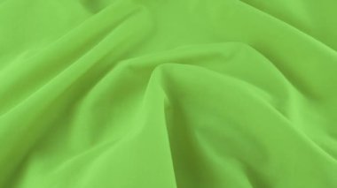 Fıstık yeşili pamuk kumaşın yumuşak kıvrımlarının üst görüntüsü. Tekstil arka planı vitrinde döner. Moda, tasarım, doğal kumaşlar, renk tonları teması üzerine arka plan.