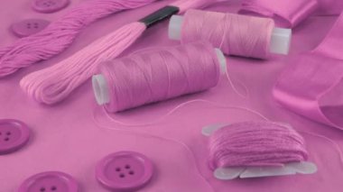 İris mor pamuk kumaş, düğmeler ve iplik makaraları, diş ipi, morun farklı tonlarında iplik. Tekstil arkaplanı görüntüleme kutusunda döner.