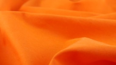 Tatlı patates turuncu pamuk kumaşının yumuşak kıvrımlarının yakın görüntüsü. Tekstil arka planı vitrinde döner. Moda, tasarım, doğal kumaşlar, renk tonları teması üzerine arka plan.