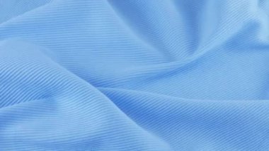 İnce shazam mavi pamuk formanın yumuşak kıvrımlarının üst görüntüsü. Tekstil arka planı vitrinde döner. Moda, tasarım, günlük konforlu giysiler için doğal kumaşlar, ev kıyafetleri, gündelik moda teması üzerine arka plan.