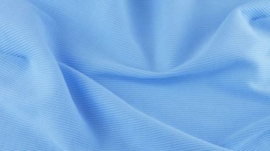 İnce shazam mavi pamuk formanın yumuşak kıvrımlarının üst görüntüsü. Tekstil arka planı vitrinde döner. Moda, tasarım, günlük konforlu giysiler için doğal kumaşlar, ev kıyafetleri, gündelik moda teması üzerine arka plan.