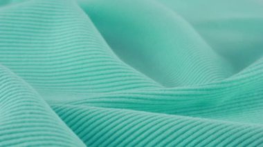 İnce Tiffany mavi pamuk formasının yumuşak kıvrımlarına yakından bakın. Tekstil arka planı vitrinde döner. Moda, tasarım, doğal kumaş teması üzerine arka plan.