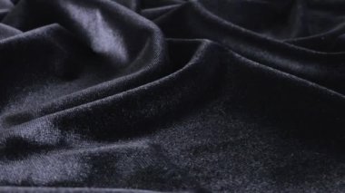 Siyah renkli grafit tonunda lüks bir kadife. Tema tasarımı, moda, terzilik ve aksesuarların tekstil geçmişi. Dönen bir vitrinde dokulu kumaşın güzel kıvrımları.