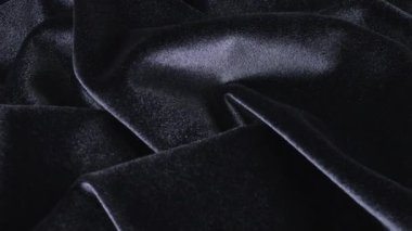 Siyah renkli grafit tonunda lüks bir kadife. Tema tasarımı, moda, terzilik ve aksesuarların tekstil geçmişi. Dönen bir vitrinde dokulu kumaşların güzel kıvrımları. Üst görünüm.