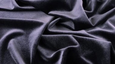 Koyu grafit rengi leylak tonunda lüks bir kadife. Tema tasarımı, moda, terzilik ve aksesuarların tekstil geçmişi. Dönen bir vitrinde dokulu kumaşların güzel kıvrımları. Üst görünüm.