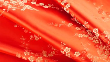 Parlak kırmızı ipek tekstil çilek rengi kumaş arka planda çiçek işlemeli doğu tarzı erik çiçeği desenli. Yumuşak kıvrımlı pırıltılar..