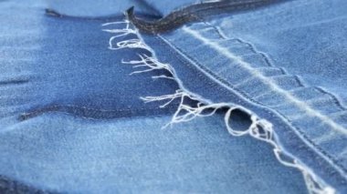 Mavi kot kumaşın yumuşak kıvrımları vitrinde dönüyor. Yeniden kullanım teması, giysi geri dönüşümü ve çevreyi korumak amacıyla tekstil arka planı.