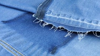 Açık mavi kot kumaşın yumuşak kıvrımları vitrinde dönüyor. Yeniden kullanım teması, giysi geri dönüşümü ve çevreyi korumak amacıyla tekstil arka planı.