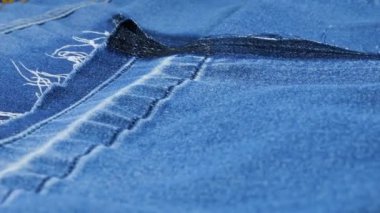 Parlak mavi kot pantolondan yapılan yırtılmadan sonra vitrinde dönen kıyafet detaylarının etkileyici dokusu. Yeniden kullanım, geri dönüşüm giysileri ve tekstil teması üzerine tekstil arka planı.