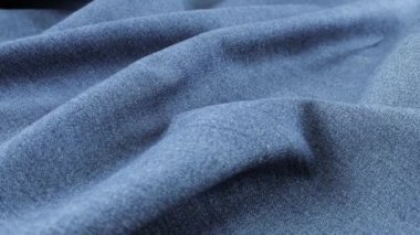 Gri-mavi kot kumaşının yumuşak kıvrımları vitrinde dönüyor. Tema tasarımı, moda, terzilik ve aksesuarların tekstil arka planı.
