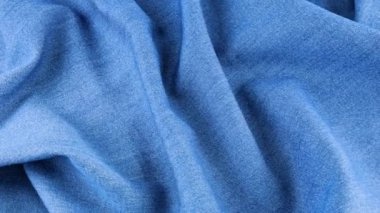 Açık mavi kot kumaşın yumuşak kıvrımları vitrinde dönüyor. Tema tasarımı, moda, terzilik ve aksesuarların tekstil geçmişi. Günlük rahat giysiler için doğal kumaşlar..