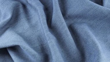 Gri-mavi kot kumaşının yumuşak kıvrımları vitrinde dönüyor. Tema tasarımı, moda, terzilik ve aksesuarların tekstil geçmişi. Üst görünüm.