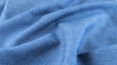 Açık mavi kot kumaşın yumuşak kıvrımları vitrinde dönüyor. Tema tasarımı, moda, terzilik ve aksesuarların tekstil geçmişi. Pamuk kumaşın dokusu ve kalitesi. Üst görünüm.