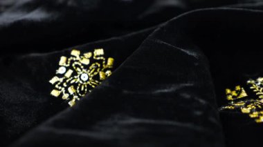 Altın işlemeli, gösterişli siyah ipek kumaş kadife kumaş. Tekstil arka planı. Tema tasarımı, moda, terzilik ve aksesuarlar. Güzel kıvrımlı kumaş.