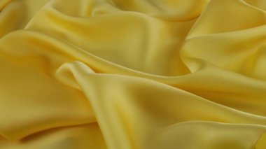 Yumuşak kıvrımlı sarı ince kumaş üzerinde doğal ipekten yapılmış üst görünüm vitrinde döndürüldü. Moda, tasarım, aksesuarlar konularında tekstil arka planı.