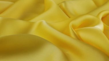 Yumuşak kıvrımlı sarı ince kumaş üzerinde doğal ipekten yapılmış üst görünüm vitrinde döndürüldü. Moda, tasarım, aksesuarlar konularında tekstil arka planı.