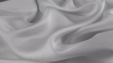 Doğal ipekten yapılmış yumuşak kıvrımlı gri ince kumaşın üst görüntüsü vitrinde dönüyordu. Moda, tasarım, aksesuarlar konularında tekstil arka planı.