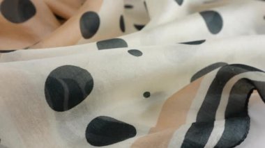 Yumuşak kıvrımlı, açık bej renginde, doğal ipekten yapılmış, siyah benekli, vitrinde döndürülmüş en ince kumaş. Moda, tasarım, aksesuarlar konularında tekstil arka planı.
