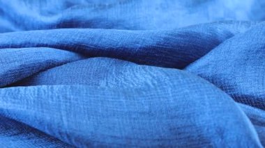 Vitrinde dönen koyu mavi ipek kumaşın yumuşak kıvrımlarında yakın çekim görüntüsü. Moda, tasarım, aksesuarlar konularında tekstil arka planı.