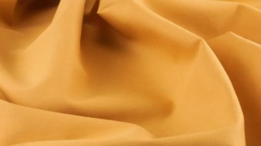 Topaz turuncu pamuk kumaşın yumuşak kıvrımlarının üst görüntüsü vitrinde döndürüldü. Tasarım teması, zanaat, el yapımı, yama çalışması, yaratıcılık teması.