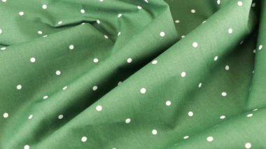 Fahişe yeşilinin yumuşak kıvrımlarının üst görüntüsü beyaz puantiyeli pamuk kumaş vitrinde döndürülmüş. Tasarım teması, zanaat, el yapımı, yama çalışması, yaratıcılık teması.