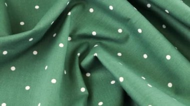 Orman yeşilinin yumuşak kıvrımlarının üst görüntüsünde beyaz puantiyeli kumaş vitrinde döndürülmüş pamuk. Tasarım teması, zanaat, el yapımı, yama çalışması, yaratıcılık teması.
