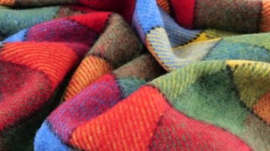 Parlak desenli çok renkli kumaşın yumuşak kıvrımlarının üst görünümü vitrinde döndürüldü. Soğuk hava, sıcak kıyafetler, konfor, aksesuarlar ve tasarım teması üzerine tekstil arka planı.