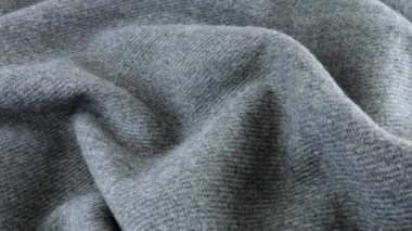 Gri yün kumaşın yumuşak kıvrımlarının üst görünümü vitrin üzerinde döndürüldü. Soğuk hava, sıcak kıyafetler, konfor, aksesuarlar ve tasarım teması üzerine tekstil arka planı.