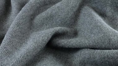 Gri yün kumaşın yumuşak kıvrımlarının üst görünümü vitrin üzerinde döndürüldü. Soğuk hava, sıcak kıyafetler, konfor, aksesuarlar ve tasarım teması üzerine tekstil arka planı.