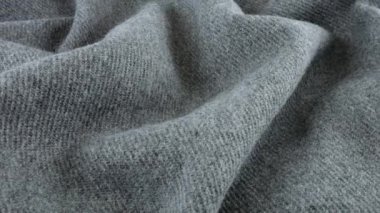 Gri yün kumaşın yumuşak kıvrımlarının üst görünümü vitrin üzerinde döndürüldü. Soğuk hava, sıcak kıyafetler, konfor, aksesuarlar ve tasarım teması üzerine tekstil arka planı.
