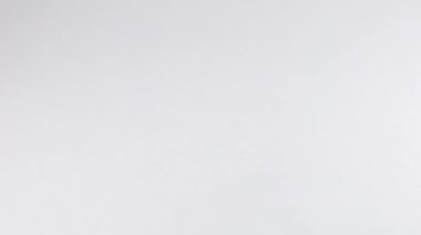 Siyah benekli doğal ipekten yapılmış açık bej renginde ince bir eşarp beyaz arkaplana yavaşça katlanır. Yavaş çekim.