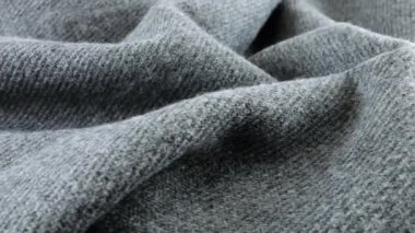 Vitrin üzerinde dönen gri yün kumaşın yumuşak kıvrımlarının yakın görüntüsü. Soğuk hava, sıcak kıyafetler, konfor, aksesuarlar ve tasarım teması üzerine tekstil arka planı.