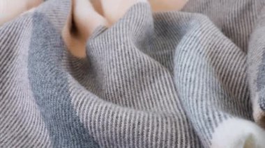 Vitrindeki yumuşak yün kumaş katlarının pastel gri-pembe renklerinin üst görüntüsü. Soğuk hava, sıcak kıyafetler, konfor, aksesuarlar ve tasarım teması üzerine tekstil arka planı.
