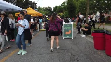 TORONTO, CANADA - 29 SEPTEMBER 2024: Davenport Rd ile Dupont Caddesi arasındaki Spadina Yolu üzerindeki Sokak Festivali, Toronto Sarımsak Festivali. Festivale katılanlar çiftlik ürünleri satan tezgahların önünden geçiyorlar.