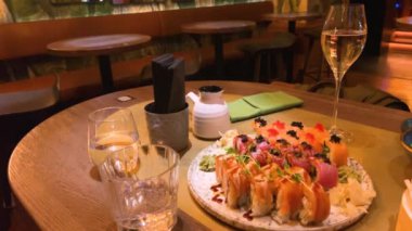 Çeşitli suşiler, börekler ve bir restorandaki masada duran diğer Asya yemekleri. Şarap ve alkollü içecekler..