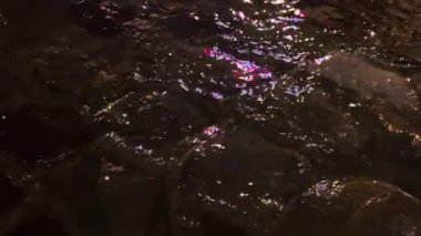 Su birikintileri, su dereleri, gece yağmur sırasında lambalardan yansıyan ışık. Şehrin kaldırımlı caddesi..