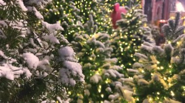 Bir gece şehrinde yeşil Noel ağaçlarına çelenklerin arkasına kar yağar..