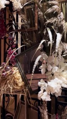 Hediyelik eşya dükkanının girişinin dekoratif unsurları ve dekorasyonları. Kış, kar yağıyor. Noel dekoru, viburum çileği, ikebana buketi. Dikey video.