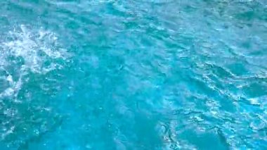 Su damlaları su yüzeyinin mavi dalgalanmalarına düşer..