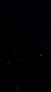 Gece gökyüzünde fırtına bulutları ve şimşekler. Dikey video.