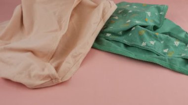 Çok renkli örülmüş kadın külotu pembe çarşafa düşer..